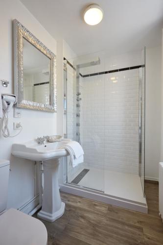 a white bathroom with a shower and a sink at The Originals Boutique, Hôtel La Colonne de Bronze, Saint-Valéry-sur-Somme in Saint-Valery-sur-Somme