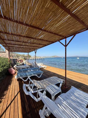 a deck with chairs and an umbrella and the ocean at Cunda Sea-View Stone Cottage & Private Beach in Ayvalık
