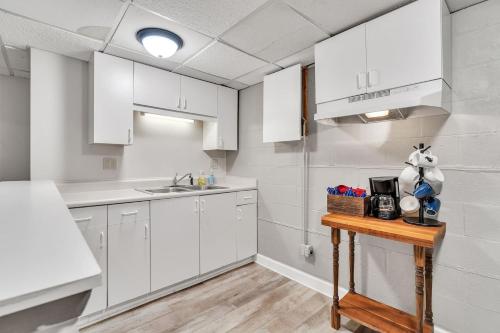 a kitchen with white cabinets and a wooden table at The Elegant Ranch by Granger Gardens in Ann Arbor