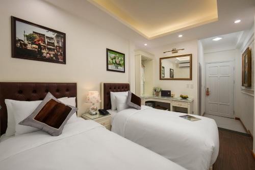 a hotel room with two beds and a mirror at TrangTrang Luxury Hotel in Hanoi