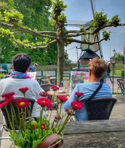two people sitting at a table in a park with flowers at De Meuleberg Boutique Suites 