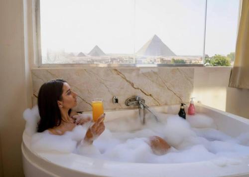 a woman sitting in a bath tub with a glass of orange juice at Bedouin Camp pyramids view INN in Cairo