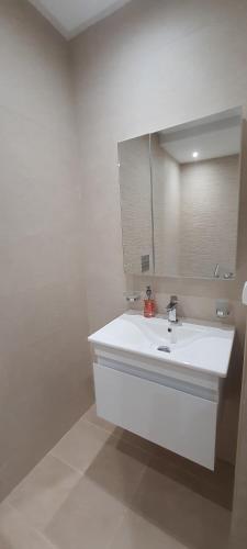 a white bathroom with a sink and a mirror at S2 apartment with sea view Costa Chatt Mariam in Chott Meriem