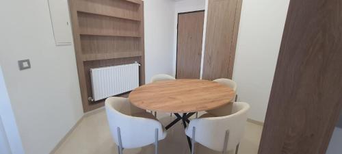 a wooden table and white chairs in a room at S2 apartment with sea view Costa Chatt Mariam in Chott Meriem