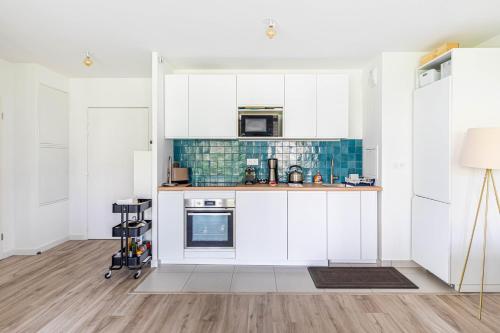 Una cocina con gabinetes blancos y un horno de estufa. en GuestReady - Charming getaway near Disneyland, en Marne-la-Vallée