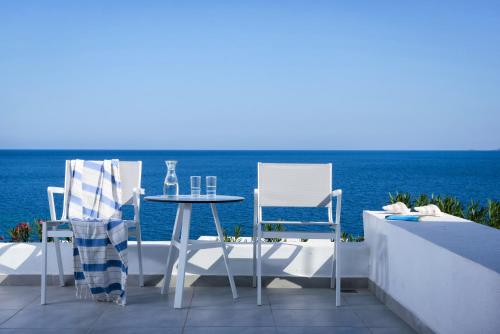 a table and chairs on a balcony with the ocean at Peninsula Resort & Spa in Agia Pelagia