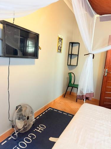 a bedroom with a fan and a tv on the wall at The Nests Busiro in Wakiso