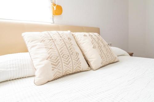 two pillows sitting on top of a white bed at Apartmento Gonzalez de Aguilar in Ayamonte