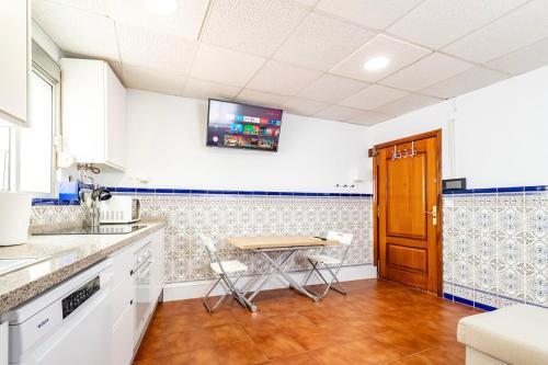 a kitchen with a table and a tv on the wall at Apartmento Gonzalez de Aguilar in Ayamonte