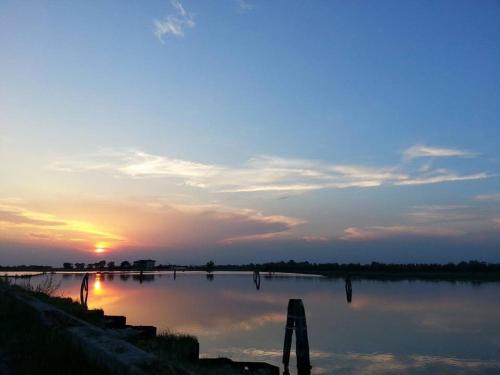 a sunset over a body of water with the sun setting at La Bricola in Cavallino-Treporti