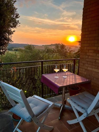 a table and two chairs on a balcony with a sunset at Agriturismo Osea in Monteriggioni
