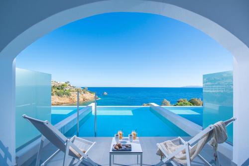 a room with a view of a swimming pool with chairs at Peninsula Resort & Spa in Agia Pelagia