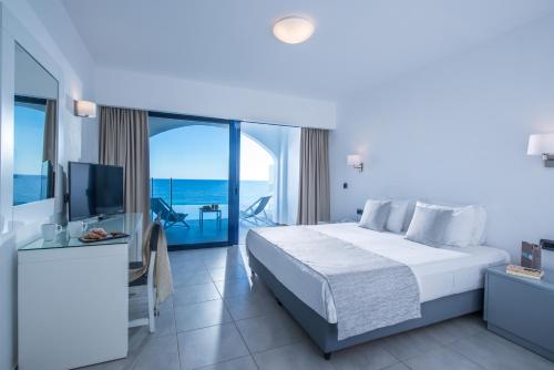 a hotel room with a bed and a television at Peninsula Resort & Spa in Agia Pelagia