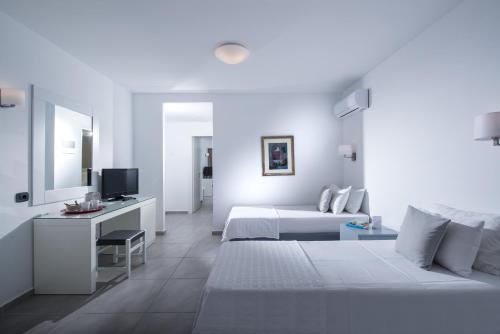 a white hotel room with a bed and a desk at Peninsula Resort & Spa in Agia Pelagia