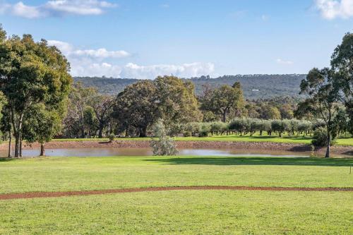a golf course with a pond and trees in the background at Petra Olive 3 in Yallingup