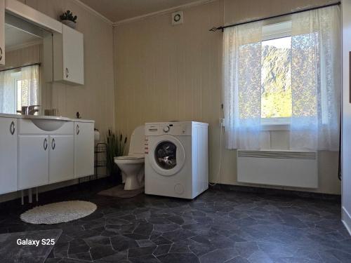a bathroom with a washing machine and a toilet at Havblikk in Gryllefjord