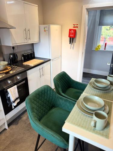 a kitchen with two green chairs and a table at The Mill House Sleep Inn in Hartlepool