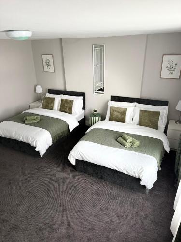a bedroom with two beds with white and green at The Mill House Sleep Inn in Hartlepool