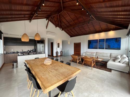 a kitchen and living room with a wooden table at Casa 05 Monte Boa Vista - Casa de Luxo na Serra com Sauna e 4 Suítes in Teresópolis