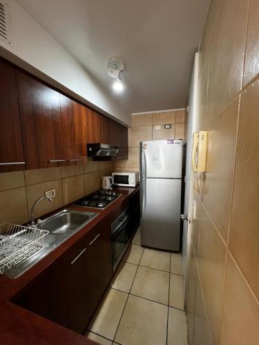 a small kitchen with a refrigerator and a sink at Dpto frente a la playa la Herradura con Piscina in Coquimbo