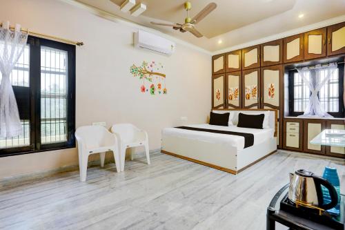 a bedroom with a bed and two white chairs at Hotel O M.P GUEST INN in Nellore