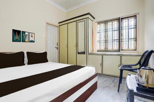 a bedroom with a bed and a chair and windows at Hotel O M.P GUEST INN in Nellore