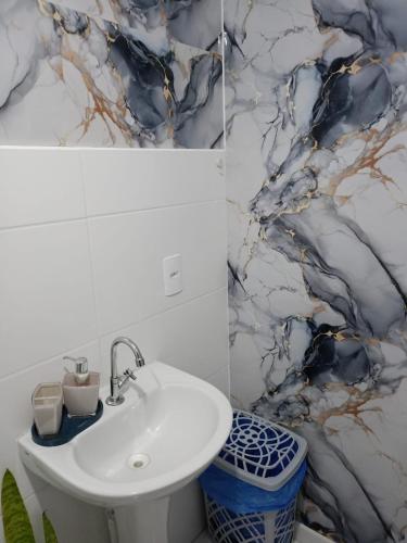a bathroom with a white sink and a marble wall at Ocean View JJ in Mongaguá
