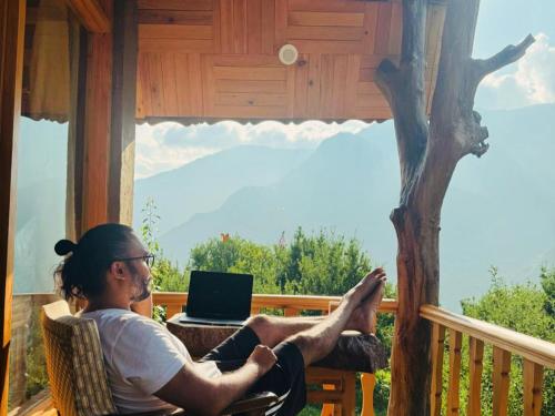 a man sitting on a porch with his feet up on a laptop at Applehill Stays - Work & Relax in Kulu