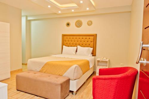 a bedroom with a bed and a red chair at Mercé Hotel in Tacna