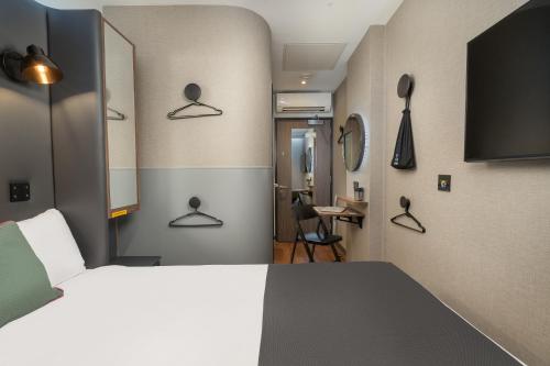 a bedroom with a bed and a room with a desk at Point A Hotel London Shoreditch in London
