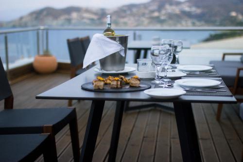 a table with a plate of food and a bottle of wine at Peninsula Resort & Spa in Agia Pelagia