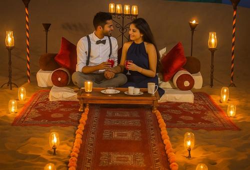 a man and a woman sitting on a couch with candles at The Carvaans Resort-Luxury Desert Camp Jaisalmer in Jaisalmer