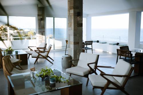 a lobby with chairs and tables and a view of the ocean at Peninsula Resort & Spa in Agia Pelagia