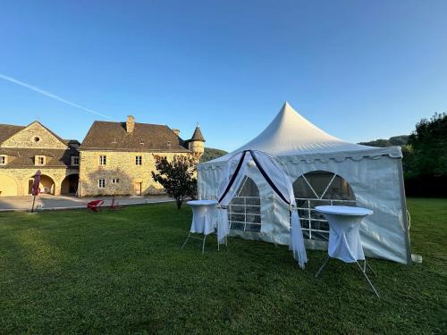 a white tent with two chairs in a yard with a castle at Château de la Falque, The Originals Relais in Saint-Geniez-dʼOlt