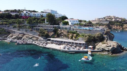an aerial view of a resort with a boat in the water at Peninsula Resort & Spa in Agia Pelagia