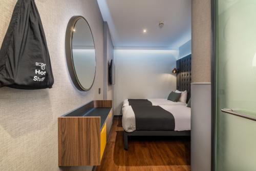 a small bedroom with a bed and a mirror at Point A Hotel London Shoreditch in London