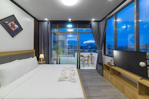 a bedroom with a large white bed and a flat screen tv at Peaceful 2 Hotel in Vientiane