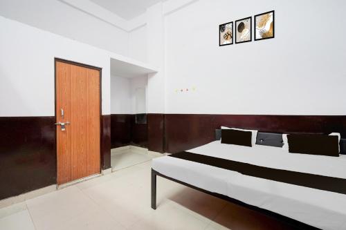 a bedroom with a bed and a wooden door at HOTEL O SP GRAND Sidhauli in Mahmūdābād