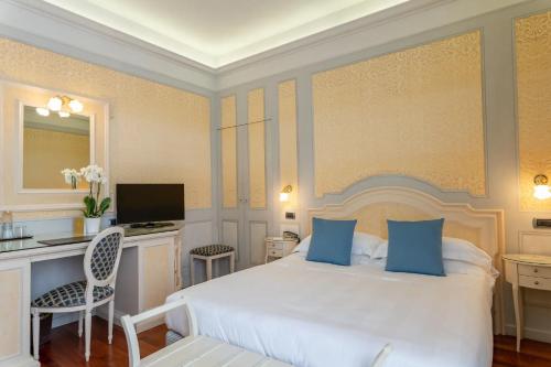 a bedroom with a large white bed with blue pillows at Phi Hotel Canalgrande in Modena