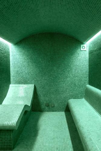 a room with green tiled walls and two beds at Peninsula Resort & Spa in Agia Pelagia