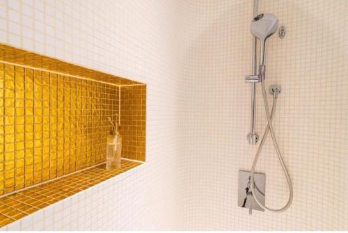 a bathroom with a shower and a yellow tile wall at Apartmens Libertas in Vienna