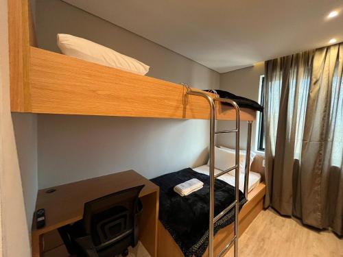a small room with a bunk bed and a desk at Flat Hotel Slaviero GRU 2 Quartos até 6p | Delfhy in Vila Gopoúva