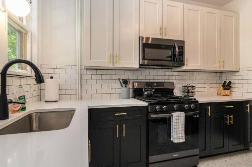 a kitchen with white cabinets and black appliances at The Royal Villa by Granger Gardens in Ann Arbor