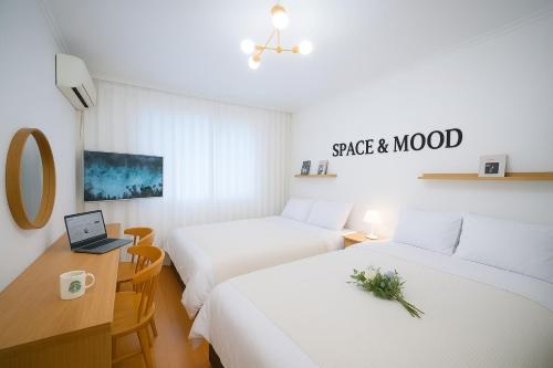 a hotel room with two beds and a desk with a laptop at SPACE & MooD in Busan
