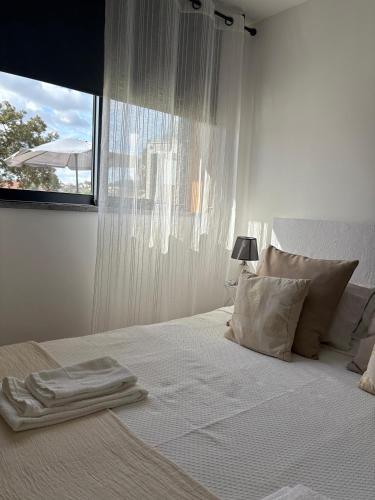 a white bedroom with a large bed with a window at Casa Moderna na Aldeia in Marco de Canaveses