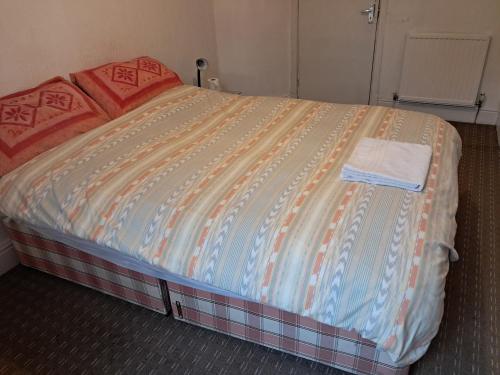a bed with orange and blue sheets in a room at Bird Song Guest House Old Trafford in Manchester