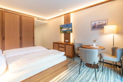 a hotel room with a bed and a table and chairs at Strandhotel Seerose in Kolpinsee