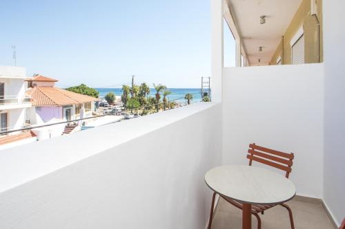 a table and chair on a balcony with a view of the ocean at Ermou 44 City Hotel in Faliraki
