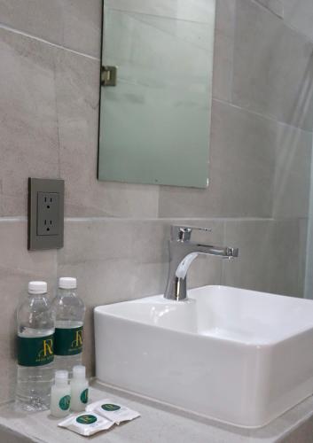 a bathroom sink with a mirror and two bottles of water at Hotel Riviera in San Juan de los Lagos