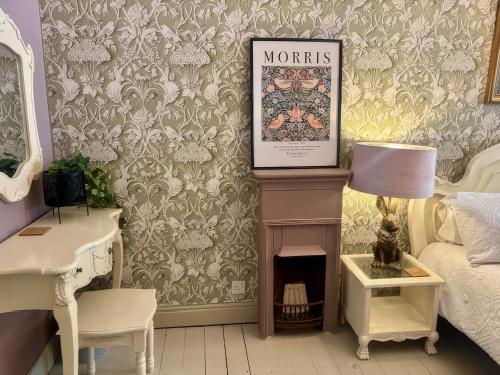 a doll room with a bed and a fireplace and wallpaper at Liberty House in Ashbourne